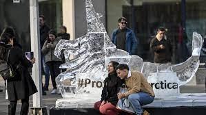 Gente posando junto a una escultura de hielo frente a la sede de la conferencia internacional de la Comisión 