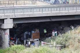 Varias personas en situación de calle conviven entre sus pocos enseres bajo un puente de Santiago 