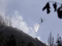 Un helicóptero lanza agua sobre un incendio en una colina de Quito - AFP