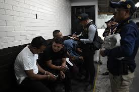 Miembros de la Inspección General de la Policía Nacional Civil Dde Guatemala vigilan a agentes detenidos - © JOHAN ORDÓÑEZ / AFP