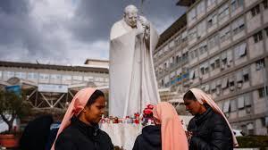 Unas monjas rezan por el papa Francisco ante la estatua del pontífice Juan Pablo II en el exterior del hospital Gemelli - AFP